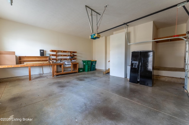 garage with a workshop area, black fridge with ice dispenser, and a garage door opener