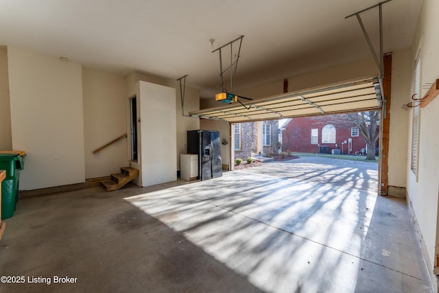 garage with black fridge with ice dispenser and a garage door opener