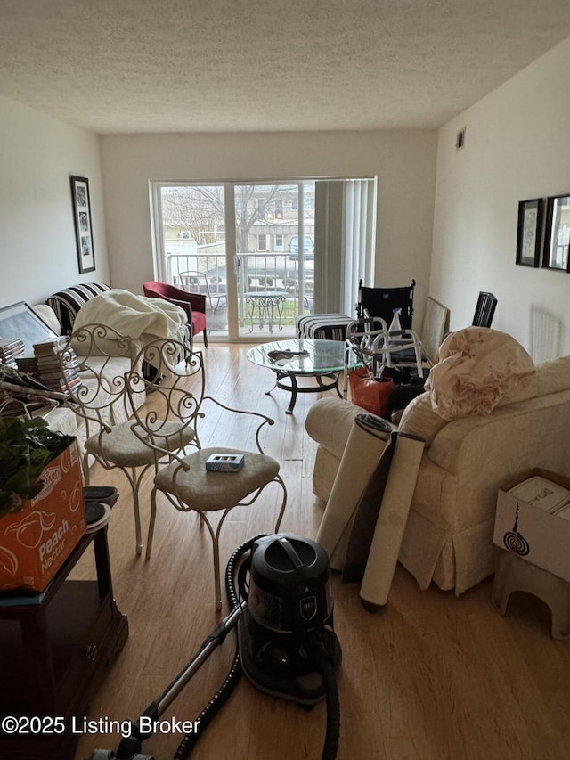 living room featuring a textured ceiling, wood finished floors, and visible vents