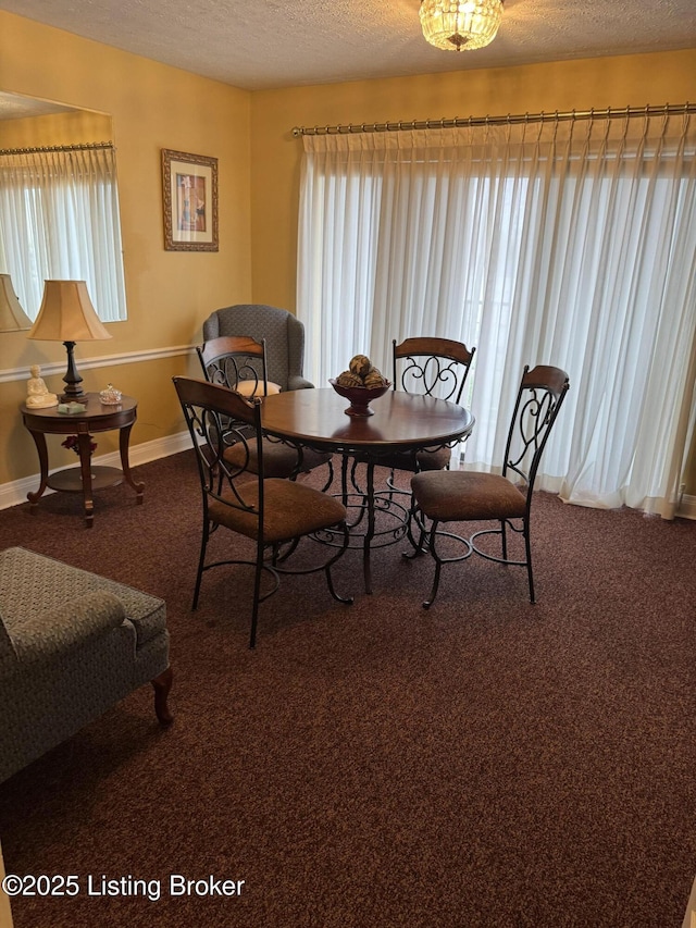 dining area with baseboards, dark carpet, and a textured ceiling