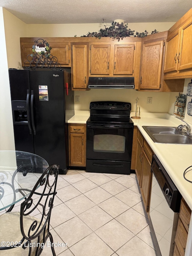 kitchen featuring a sink, light countertops, ventilation hood, black appliances, and brown cabinetry