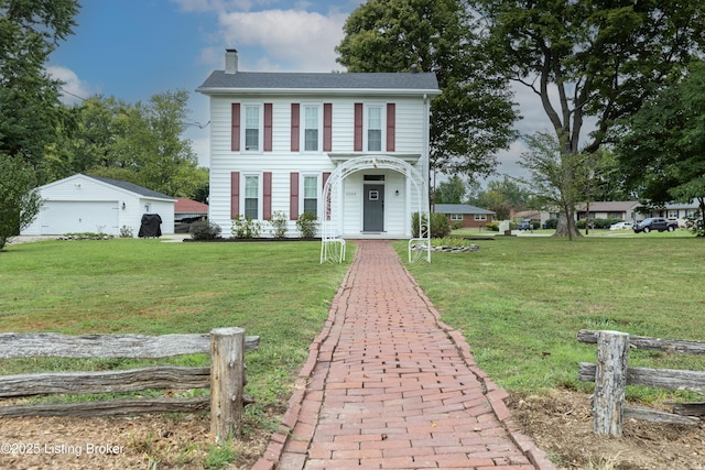 view of front of property featuring an outbuilding, a front lawn, a detached garage, and a chimney