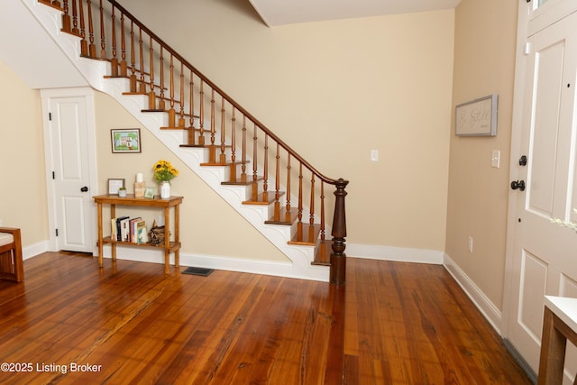 foyer with stairway, visible vents, baseboards, and hardwood / wood-style floors