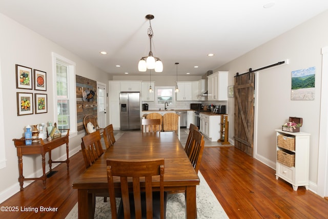 dining area with recessed lighting, a barn door, baseboards, and dark wood finished floors