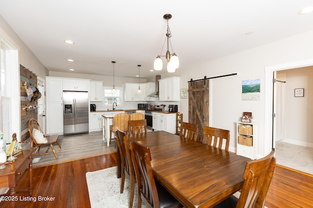 dining room featuring a barn door, recessed lighting, wood finished floors, and baseboards