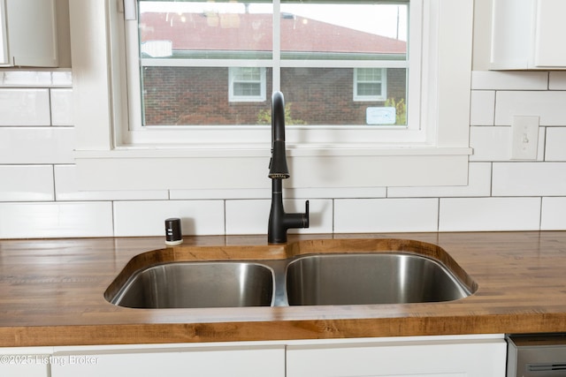 details featuring white cabinetry, tasteful backsplash, and a sink