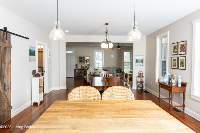 dining room with baseboards, dark wood-type flooring, and a barn door