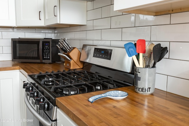 room details featuring stainless steel appliances, backsplash, butcher block countertops, and white cabinets