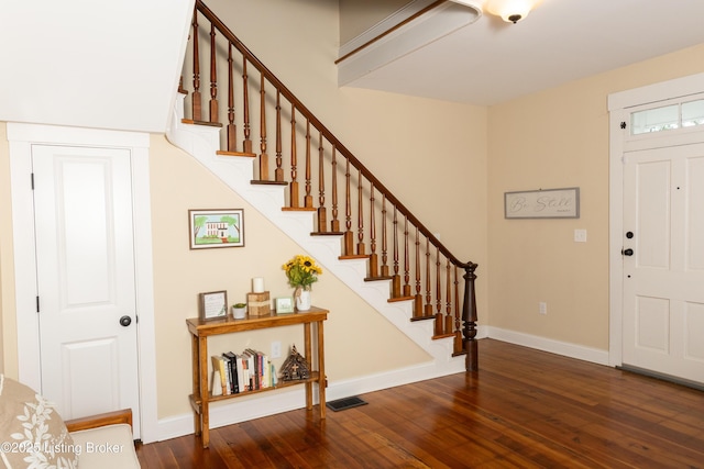 foyer entrance with visible vents, baseboards, stairway, and hardwood / wood-style flooring