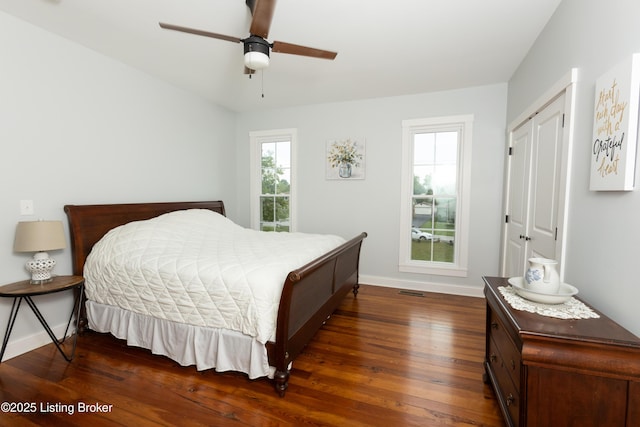 bedroom featuring a closet, baseboards, dark wood-style floors, and a ceiling fan