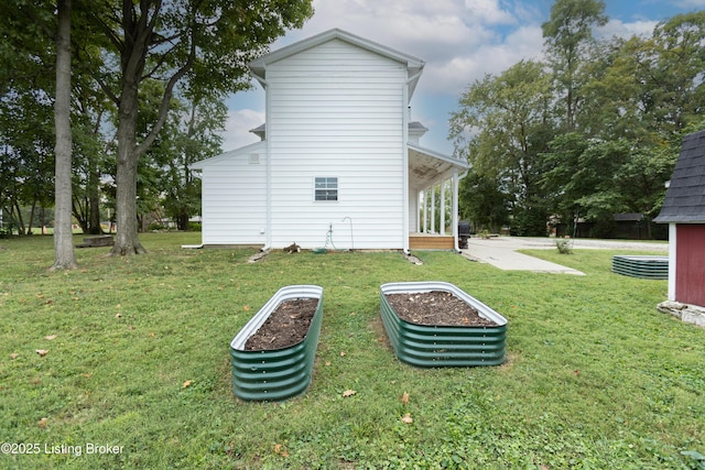 rear view of property featuring a yard and a garden