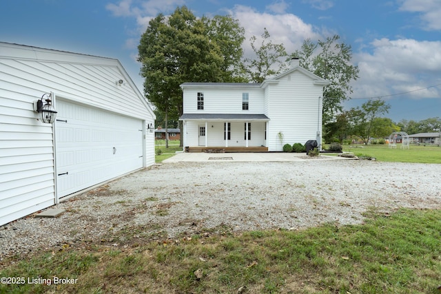 exterior space with an outbuilding, a porch, a front lawn, and a garage