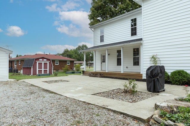 back of property with a storage shed, an outbuilding, and covered porch