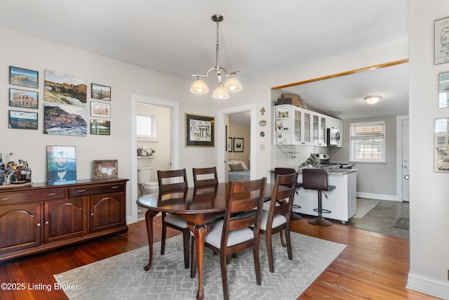 dining space featuring a notable chandelier, dark wood finished floors, and baseboards