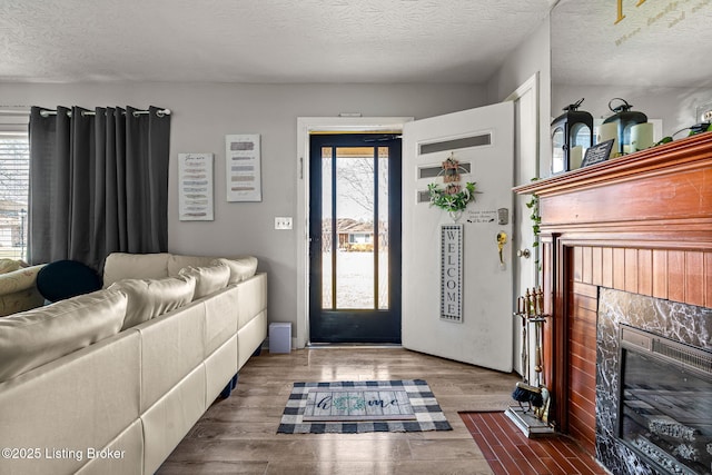 foyer featuring a wealth of natural light, a glass covered fireplace, a textured ceiling, and wood finished floors