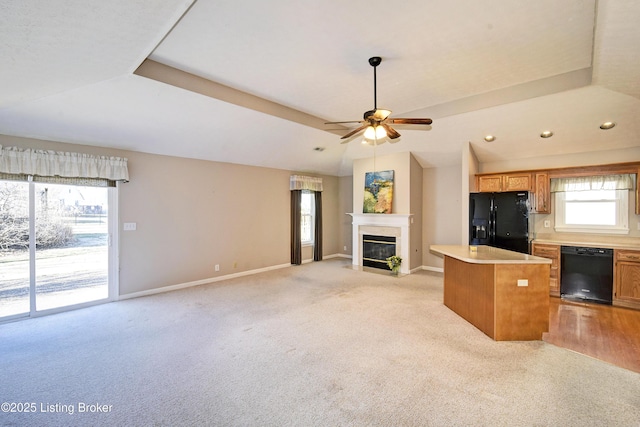 unfurnished living room featuring light carpet, baseboards, a ceiling fan, vaulted ceiling, and a fireplace