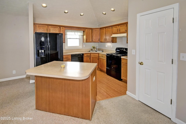 kitchen featuring under cabinet range hood, vaulted ceiling, light countertops, black appliances, and a sink