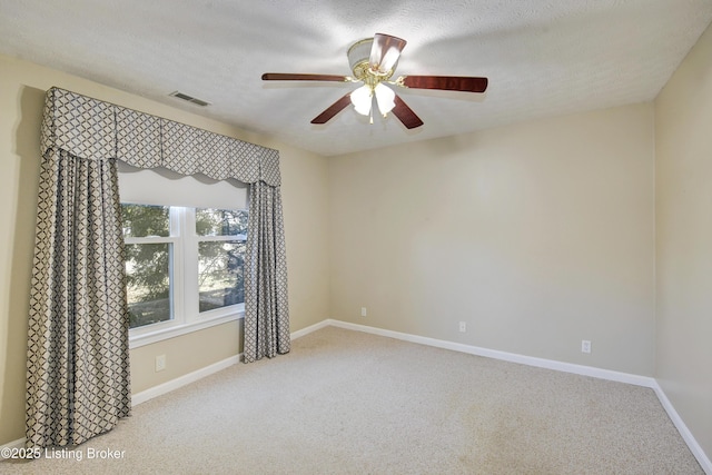 spare room featuring a textured ceiling, ceiling fan, carpet flooring, visible vents, and baseboards