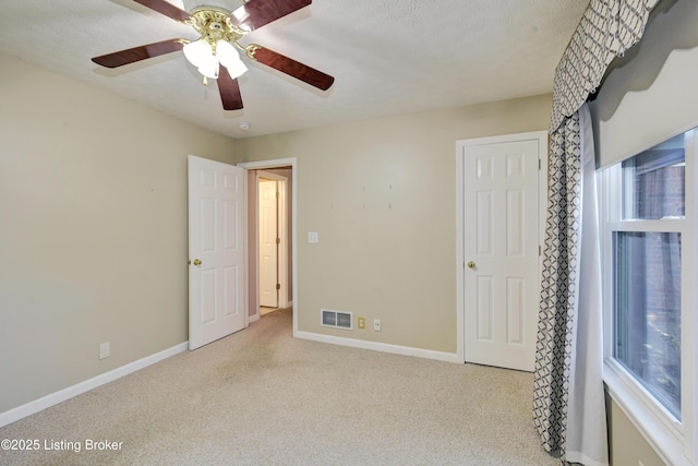 unfurnished bedroom featuring carpet floors, visible vents, ceiling fan, a textured ceiling, and baseboards