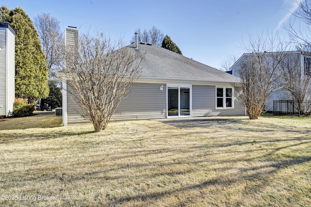 rear view of property featuring a shingled roof and a yard