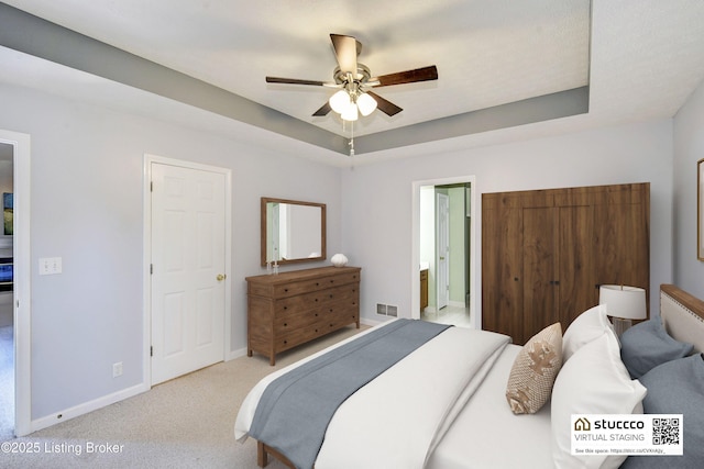 bedroom with visible vents, baseboards, a raised ceiling, ceiling fan, and carpet