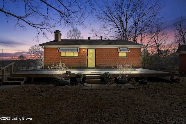 rear view of house featuring brick siding, a chimney, and a wooden deck