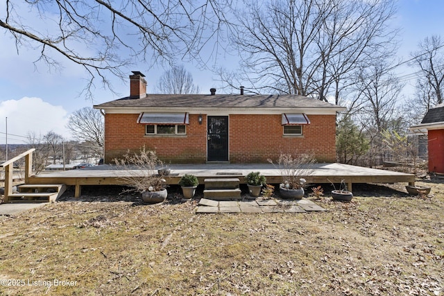 rear view of house featuring brick siding, a chimney, and a wooden deck