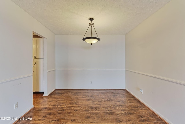 unfurnished room with a textured ceiling, baseboards, and wood finished floors