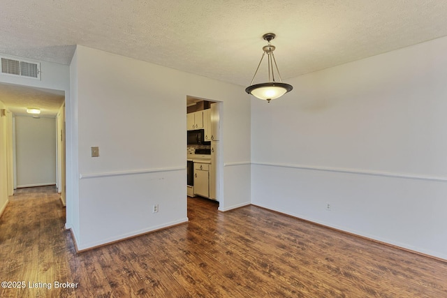 spare room featuring dark wood-style floors, a textured ceiling, visible vents, and baseboards