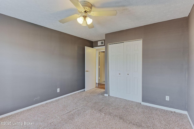 unfurnished bedroom featuring a textured ceiling, carpet flooring, visible vents, baseboards, and a closet