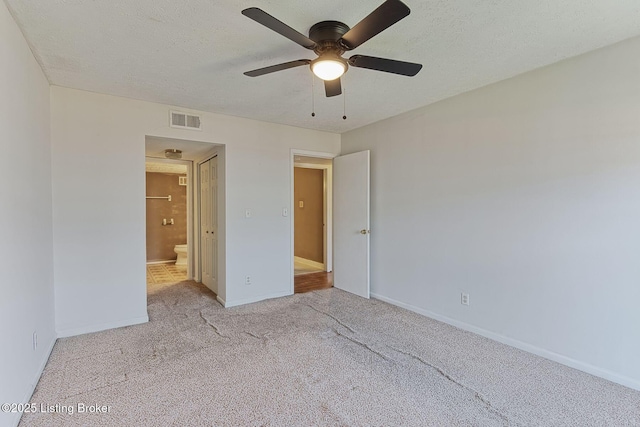 unfurnished bedroom featuring carpet, visible vents, a textured ceiling, and baseboards