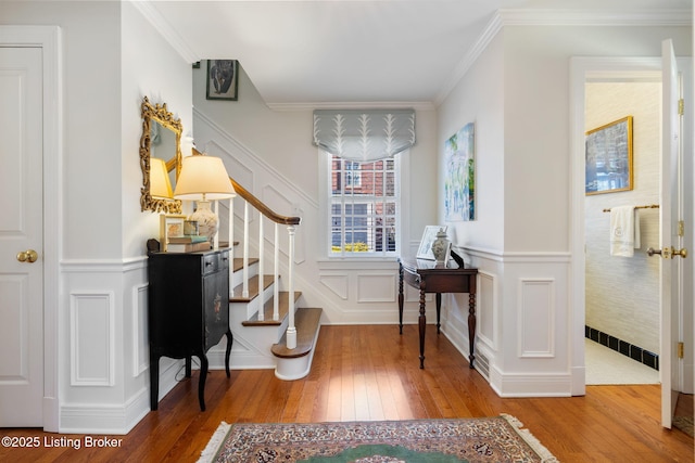 interior space with ornamental molding, wood-type flooring, wainscoting, and stairway