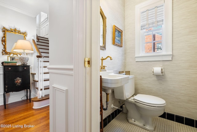 half bath with toilet, crown molding, and tile patterned floors