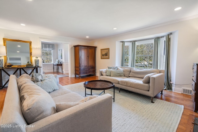 living area featuring recessed lighting, visible vents, wood finished floors, and ornamental molding