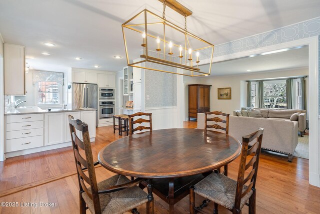 dining room with wallpapered walls, a wainscoted wall, light wood-style flooring, a chandelier, and recessed lighting