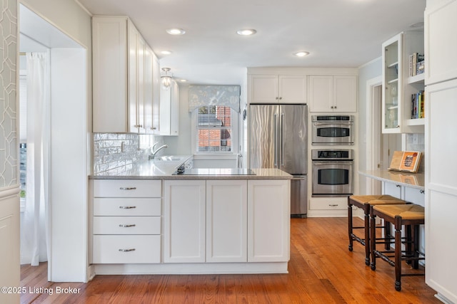 kitchen with stainless steel appliances, white cabinets, and light wood finished floors