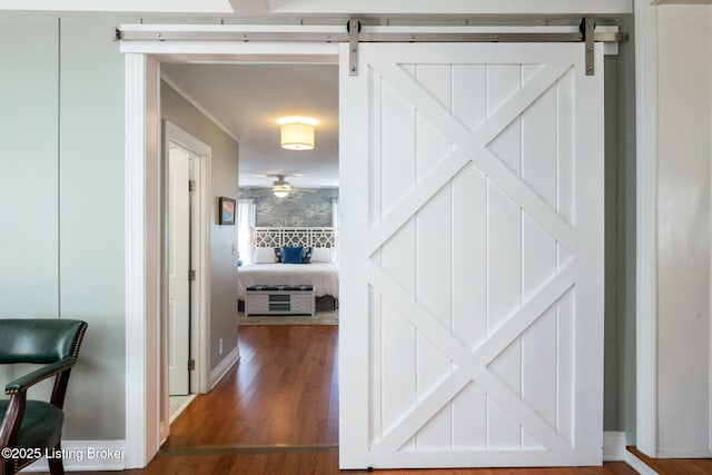 corridor with dark wood finished floors and a barn door