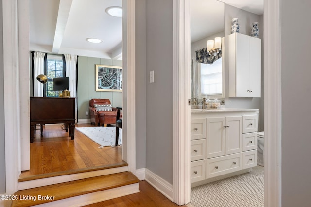 bathroom with toilet, beamed ceiling, vanity, and baseboards