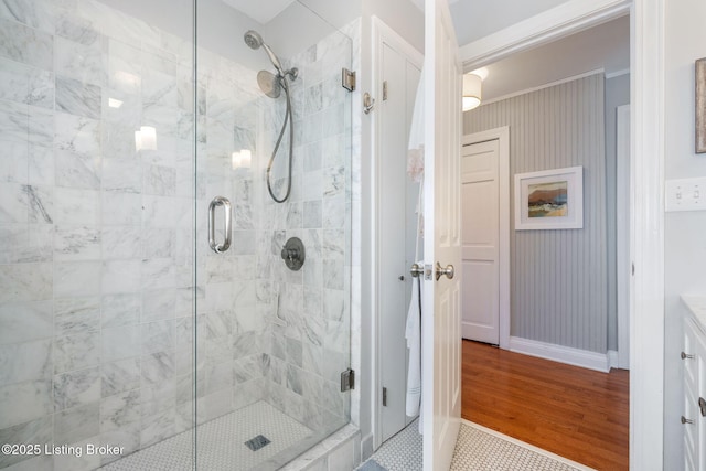 bathroom featuring a shower stall, baseboards, wood finished floors, and ornamental molding