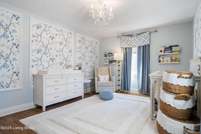 bedroom with baseboards, wood finished floors, and a notable chandelier