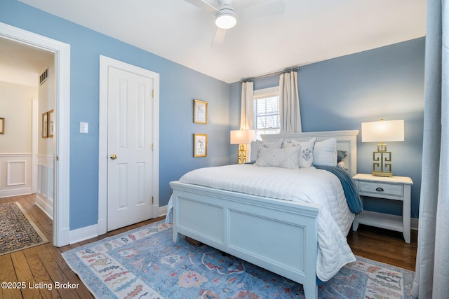 bedroom with a ceiling fan, wood finished floors, visible vents, and baseboards