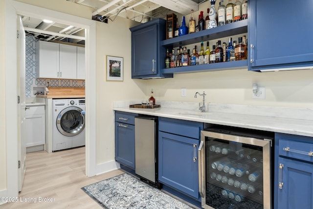 bar with beverage cooler, a sink, light wood-type flooring, washer / clothes dryer, and indoor wet bar