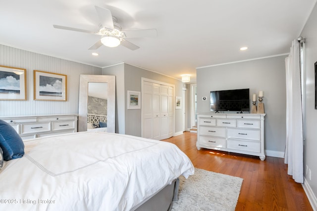 bedroom with baseboards, a ceiling fan, ornamental molding, wood finished floors, and a closet