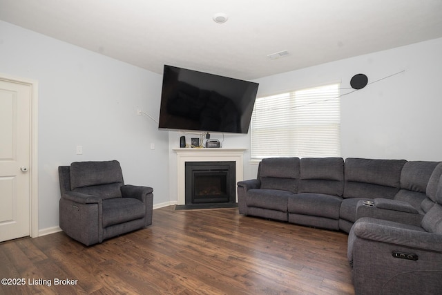 living room with dark wood-style floors, baseboards, and a fireplace with flush hearth