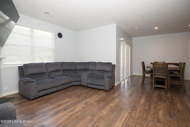 living area featuring visible vents, baseboards, and wood finished floors