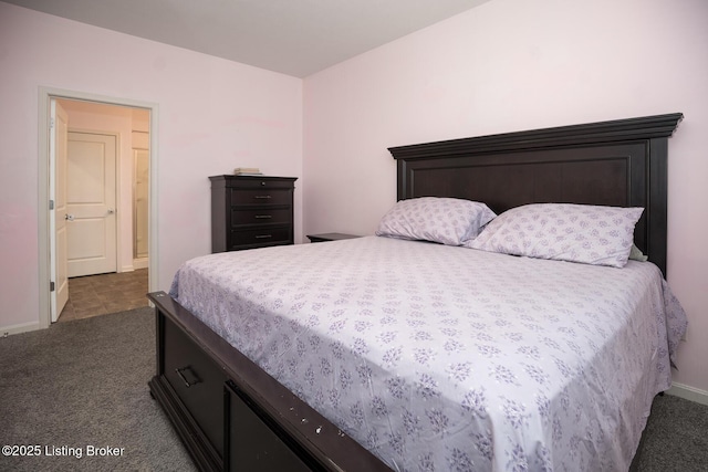 bedroom with dark colored carpet and baseboards
