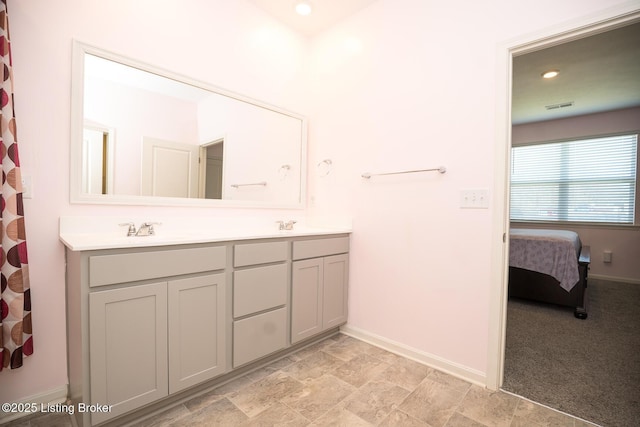 ensuite bathroom featuring double vanity, visible vents, a sink, ensuite bath, and baseboards