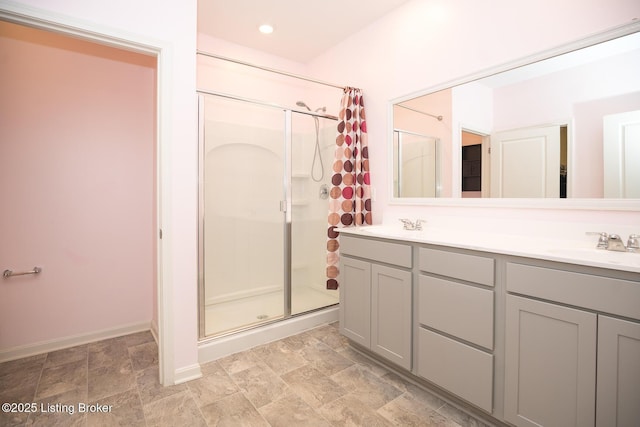 bathroom with double vanity, recessed lighting, a stall shower, a sink, and baseboards