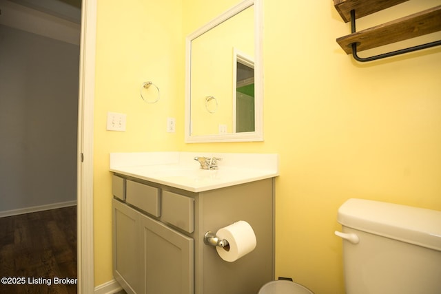 bathroom featuring wood finished floors, vanity, toilet, and baseboards