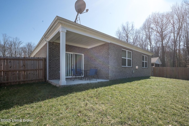 back of house with fence, a lawn, a patio, and brick siding